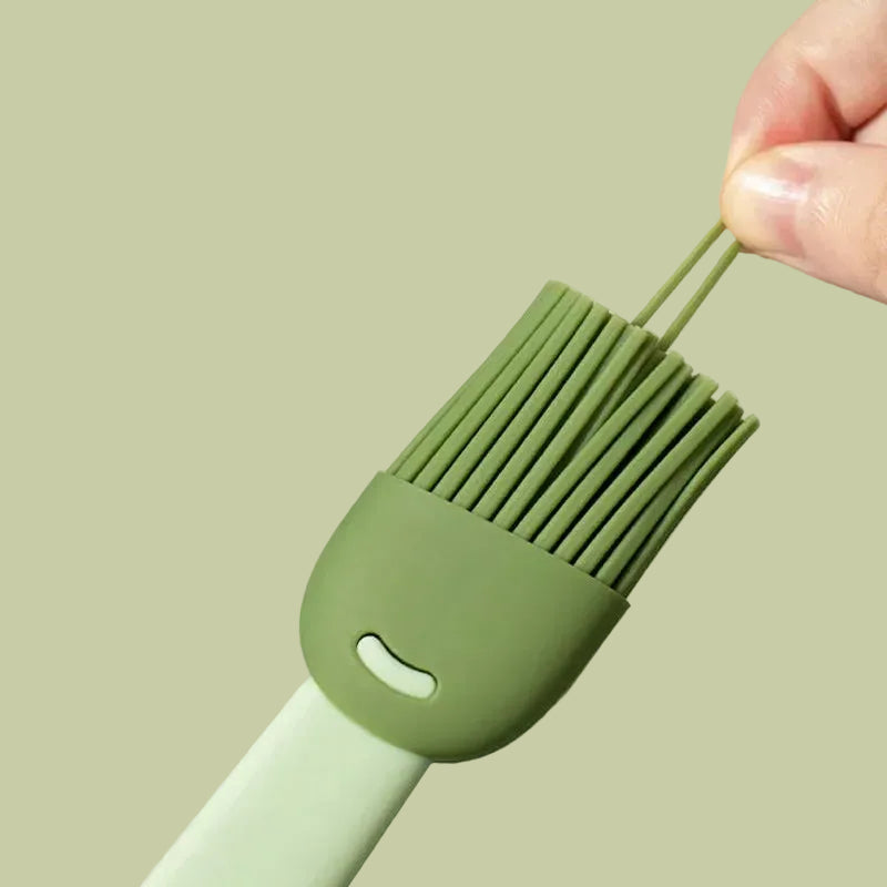 Green silicone brush held by a hand against a light green background
