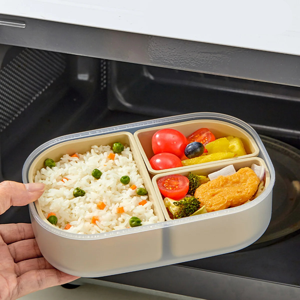 Meal prep container with rice, vegetables, and fish held above an open oven.