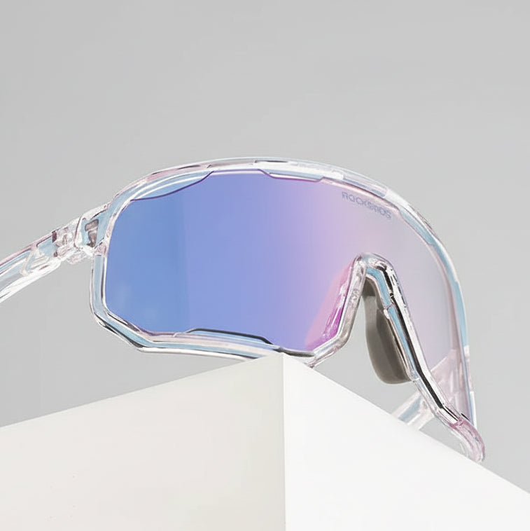 Clear sunglasses with blue-tinted lenses on a white surface with a blue sky background, featuring the RockBros brand.
