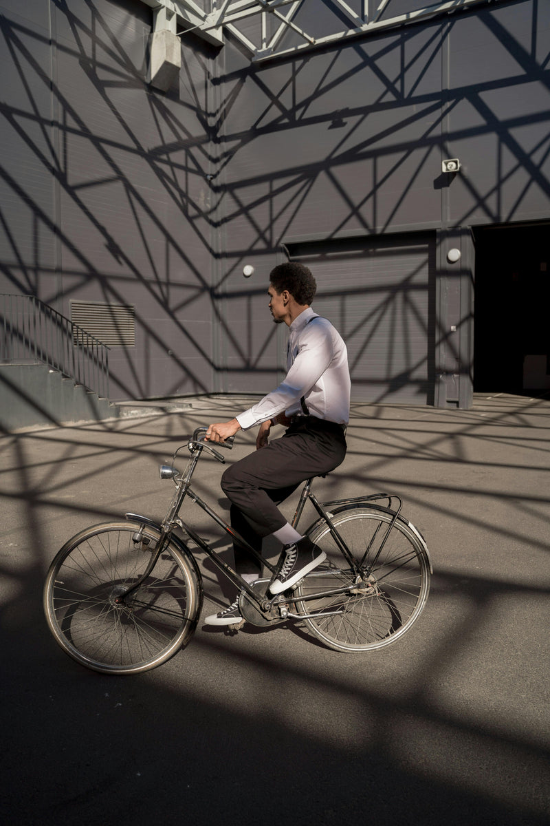 Man riding a bicycle in an industrial setting with geometric shadows on the wall.