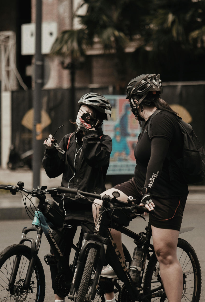 Two people on bicycles wearing helmets in an urban setting