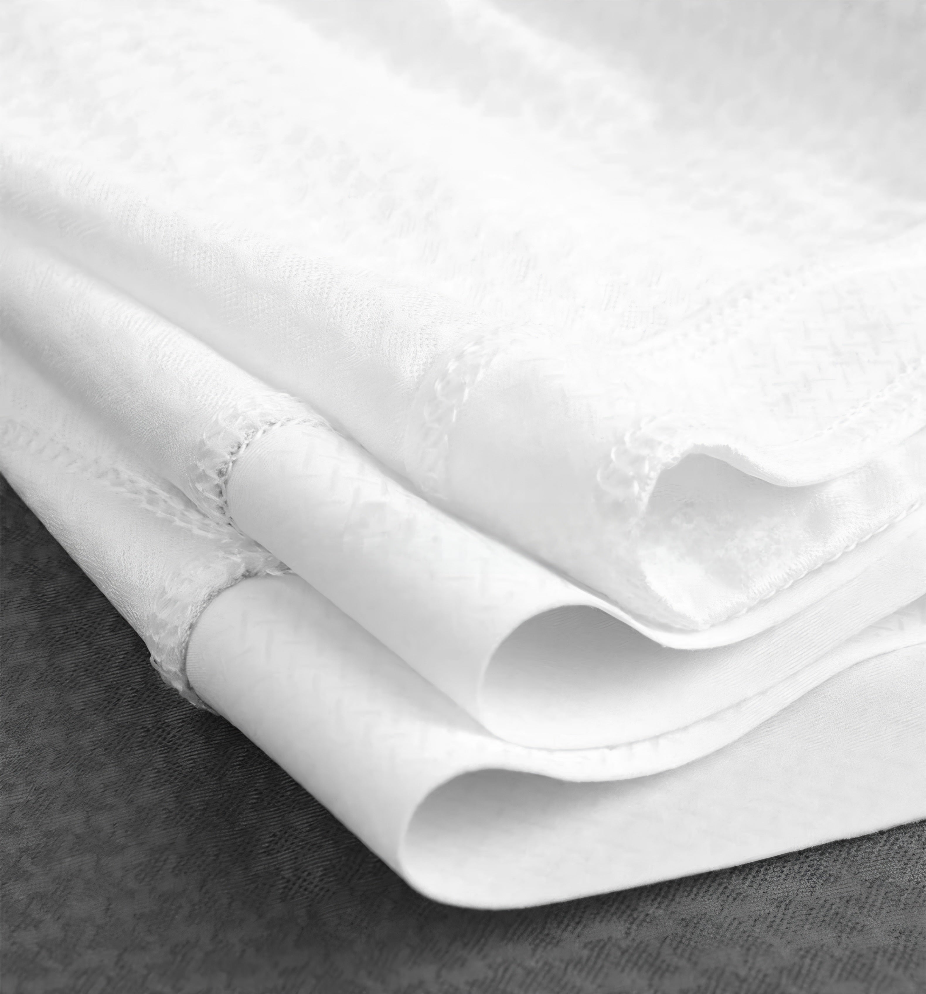 Close-up of white fabric with a textured pattern on a dark surface